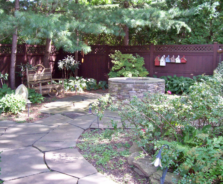 Stone fire pit centerpiece on a flagstone patio with garden borders
