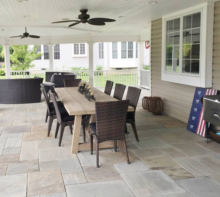 Covered bluestone patio with farmhouse dining table and ceiling fans