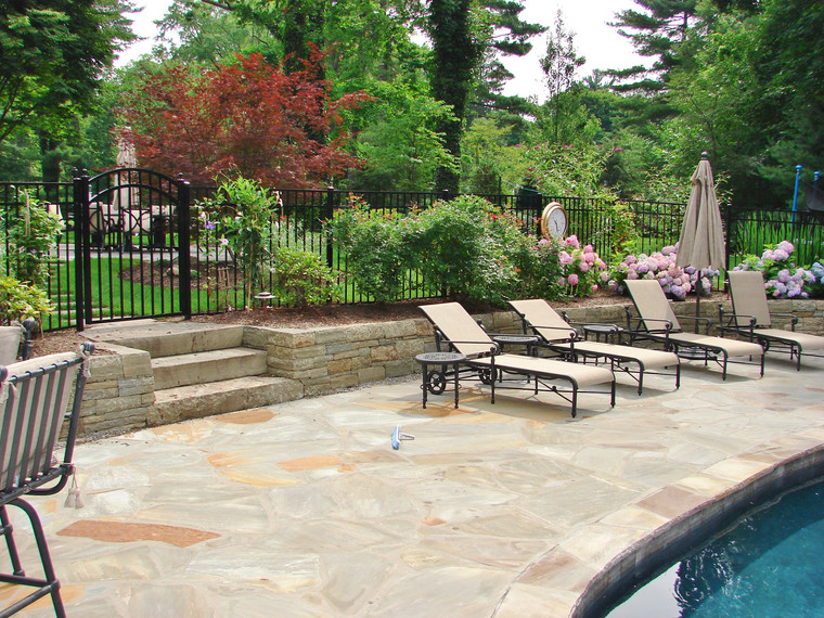 Flagstone pool patio with chaise lounges and stone retaining wall