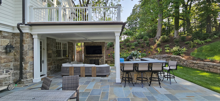 Covered bluestone patio with outdoor fireplace, lounge seating, and bar