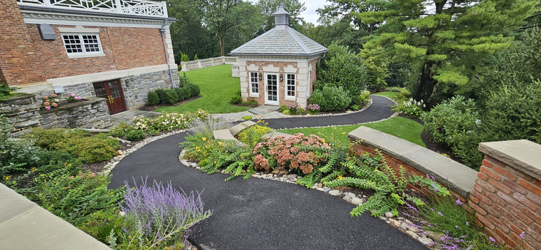 Curved garden bed with mums, lavender, and ornamental grasses around a stone path