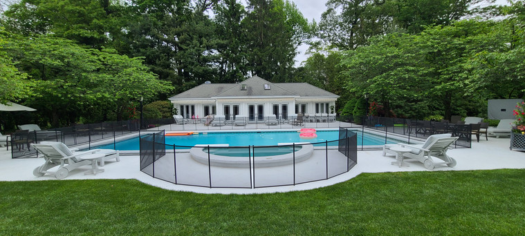 Classic rectangular pool with safety fence and pool house backdrop