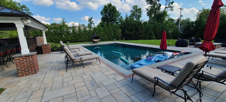 Bluestone pool patio with cabana bar and lounge chairs under blue sky